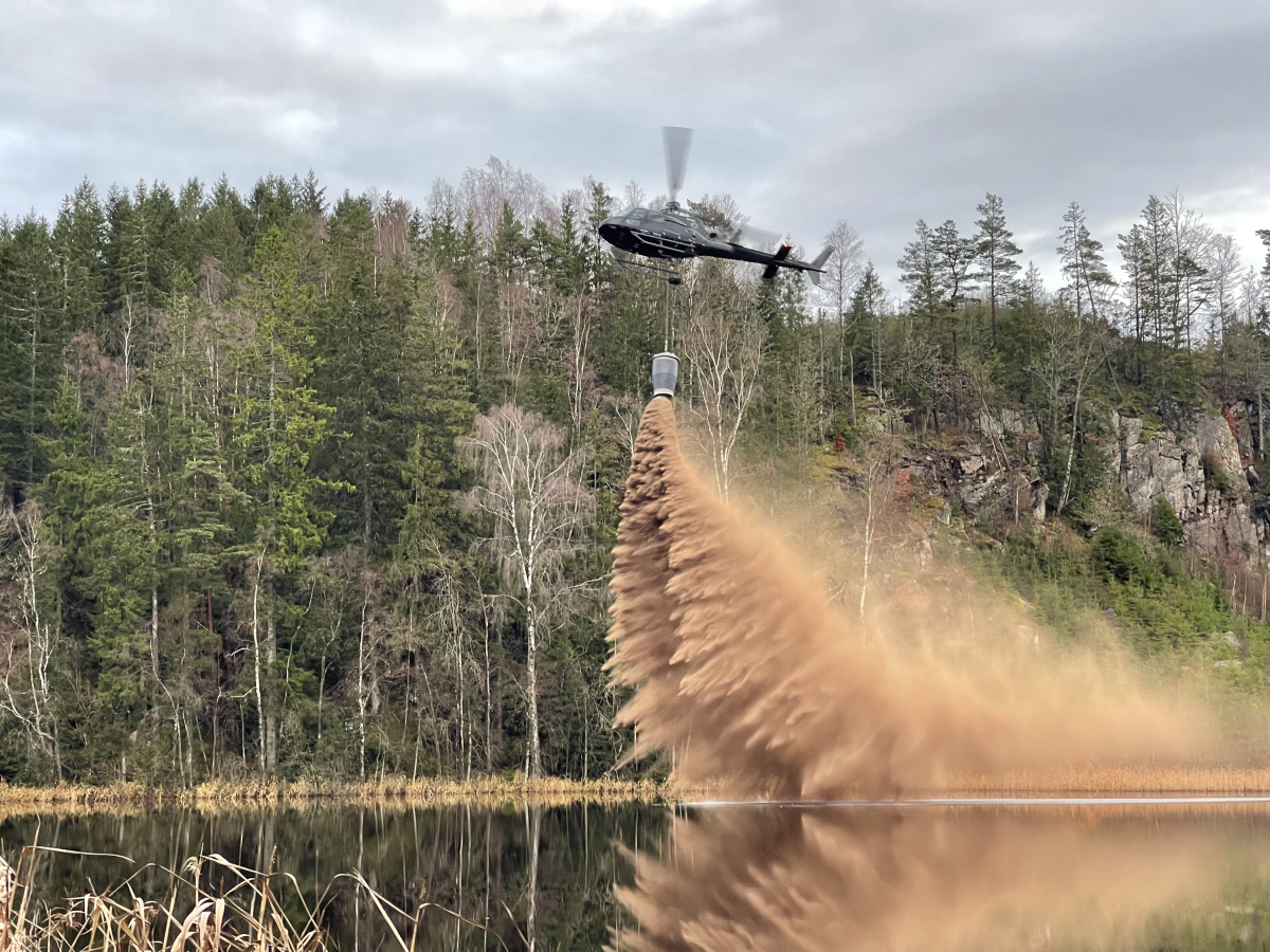 Helikoptern genomför kalkning på en sjö.