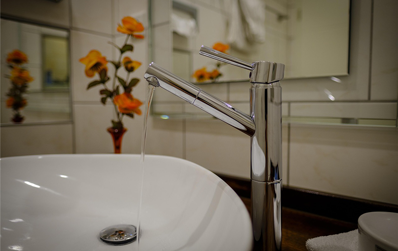 Bilden visar en vattenkran som rinner i ett badrum.