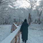 Bilden visar en person som går längs med ett snötäckt Ödet i Torsås. På träden är grenarna vita av snö lika så är marken täckt av snö.