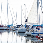 Bilden visar båtar som ligger till kaj i Bergkvara hamn med en helt vit himmel.